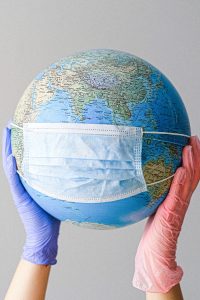 gloved hands holding a globe with a face mask