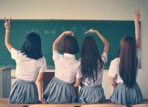 four girls in school uniform doing hand signs
