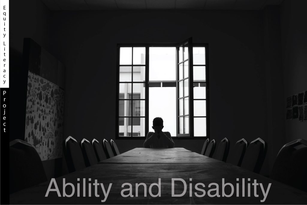 A gloomy black and white photograph of a student sitting alone at a long table in an empty classroom. The student is in full silhouette while back lit by a bright open window far in the distance. The words Ability and Disability are captioned at the bottom in a transparent text.